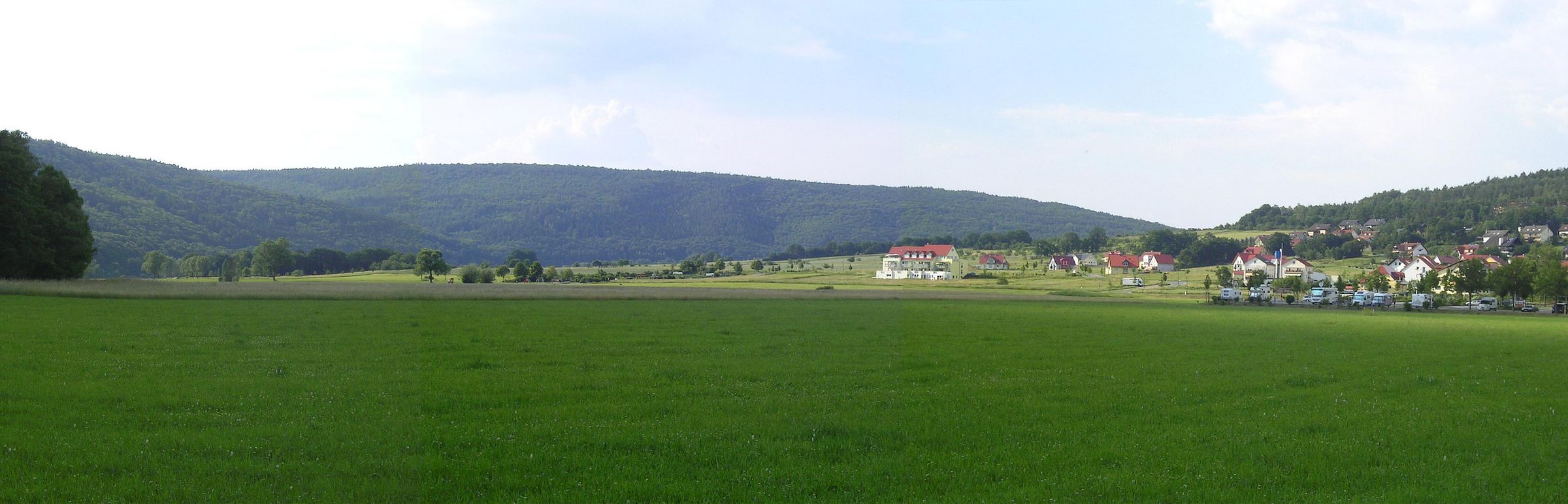 Blick auf die Saalewiesen bei Bad Bocklet, eine weitreichende, grüne Landschaft im Sonnenschein