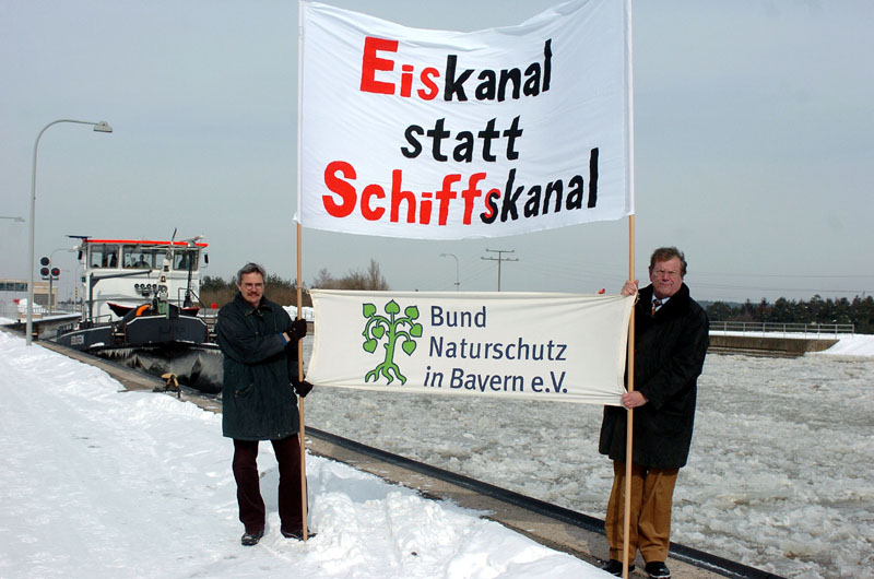 Bild von einem Protest. Auf dem Spruchband steht "Eiskanal statt Schiffskanal"