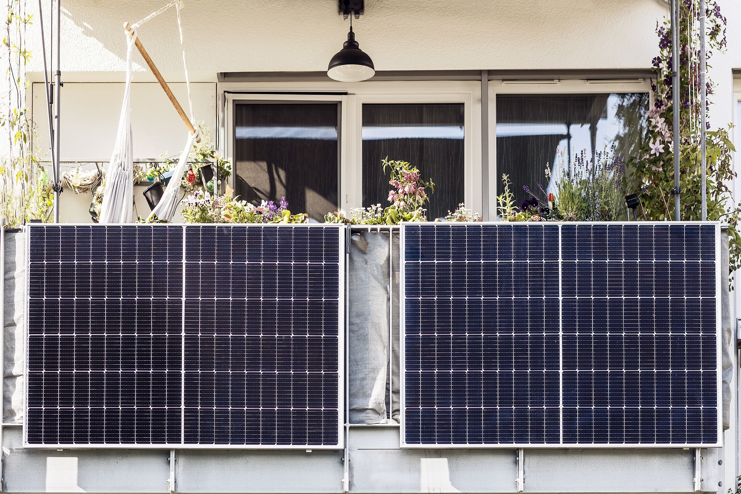 Ein Balkonkraftwerk am Geländer eines pflanzenbewachsenen Balkons: Die kleinen Anlagen lassen sich ohne großen Aufwand installieren. (Foto: Maryana/stock.adobe.com)