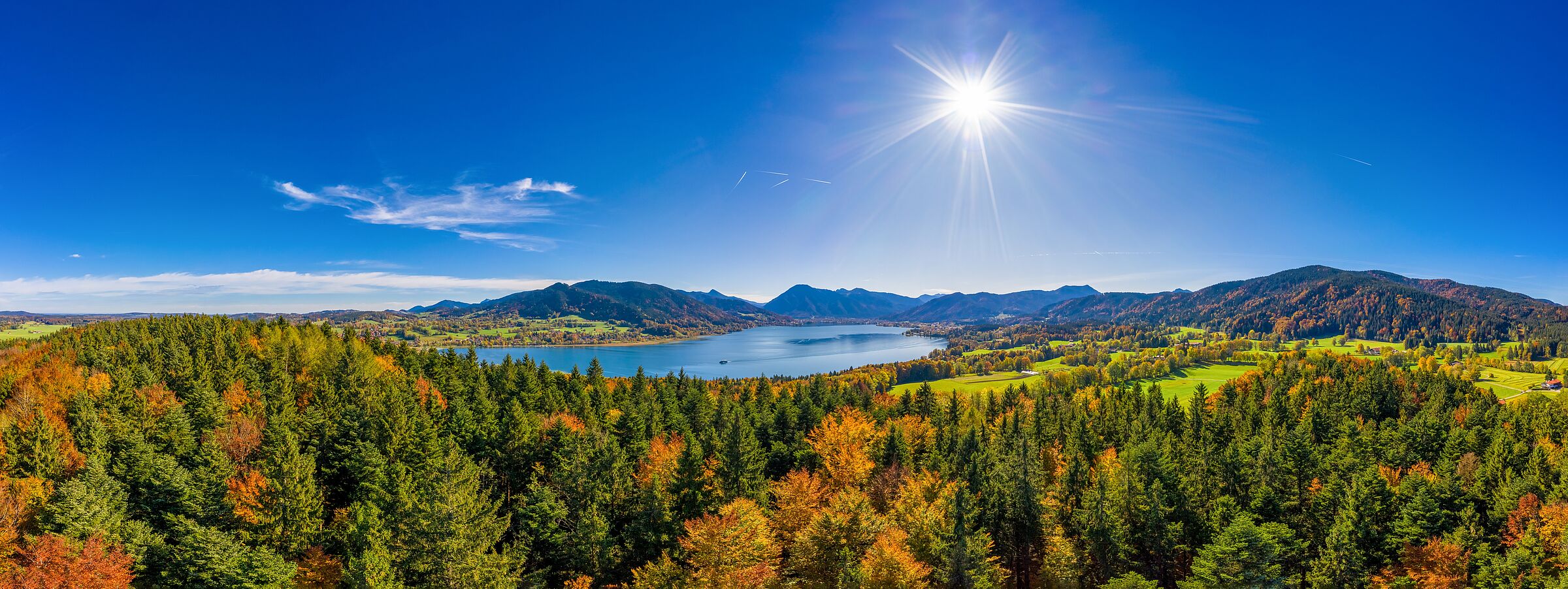 Berwald Bayern: Blick auf einen herbstlich gefärbte Laubbäume, im Hintergrund Bergkulisse und Hänge mit Nadelbäumen und einzelnen Laubbäumen