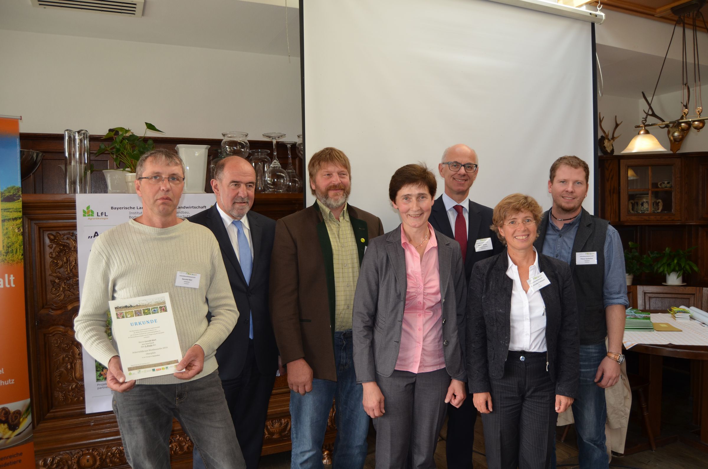 Eine Gruppe von sechs Leuten steht in einem Saal. Einer hält eine Urkunde in den Händen. Die Preisverleihung für den Ackerwildkraut-Wettbewerb 2016 fand im September in Regensburg statt. (Tim Fluhrer/BN)