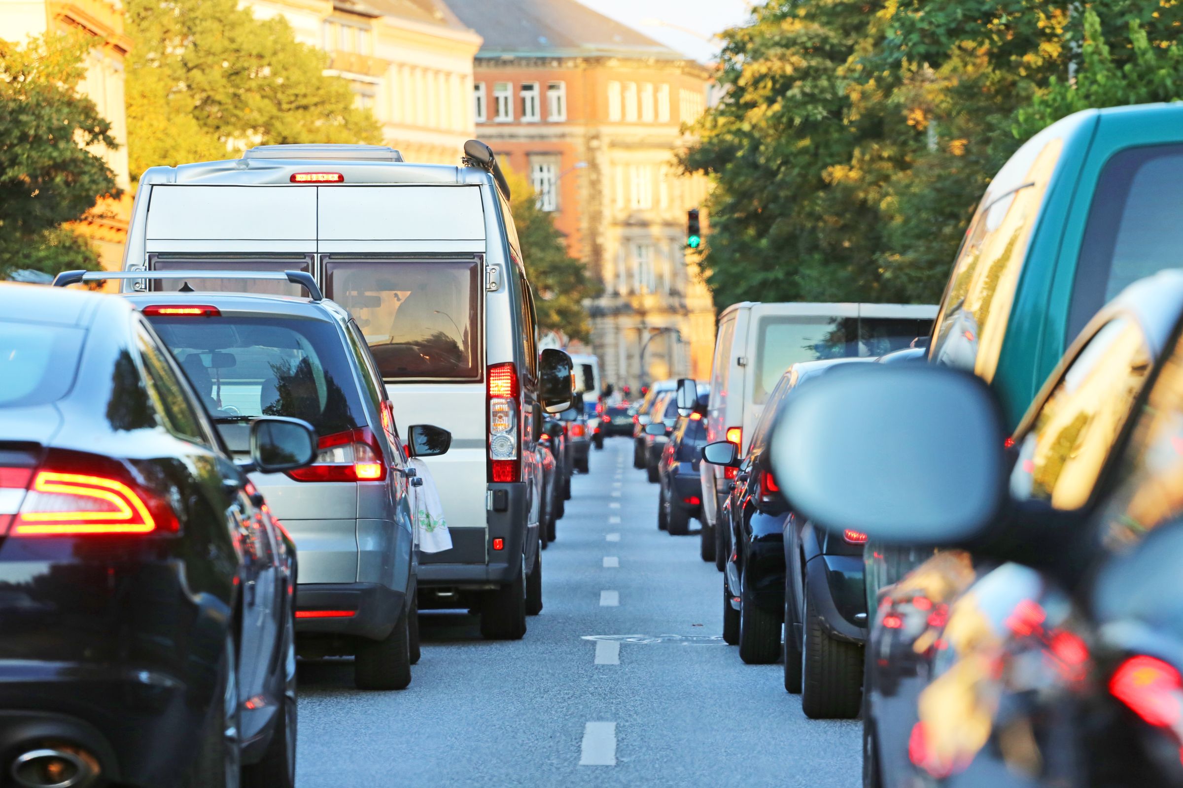 Autos stauen sich zweispurig in langen Schlangen vor einer Ampel: Der wachsende Autoverkehr fordert immer mehr Platz und führt zu wachsenden Luft-, Lärm- und Umweltproblemen. (Bild: Adobestock/Kara)