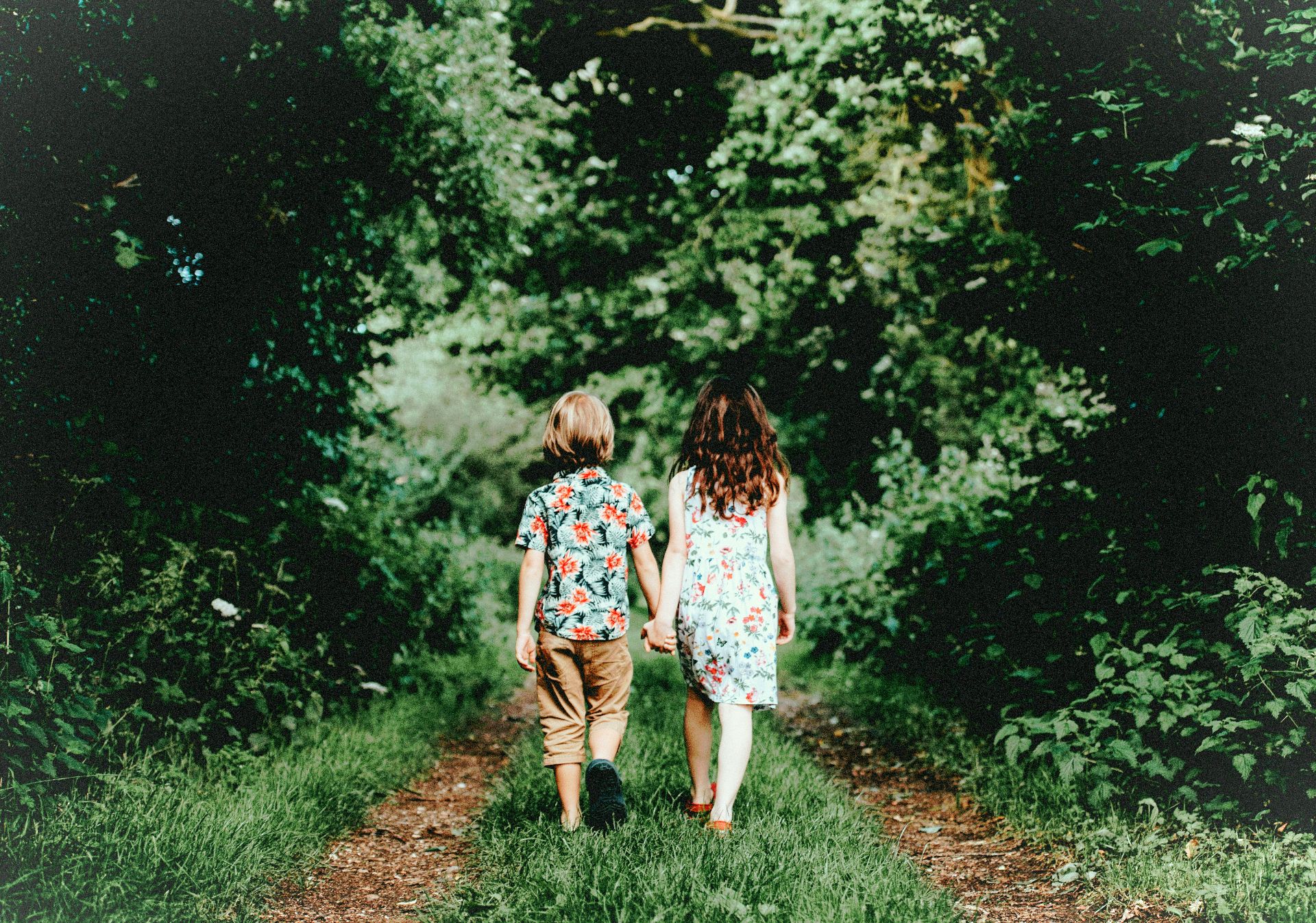 Zwei Kinder gehen Hand in Hand einen Waldweg entlang. (Bild: Annie Sprat/unsplash) Zwei Kinder gehen Hand in Hand einen Waldweg entlang. (Bild: Annie Sprat/unsplash)
