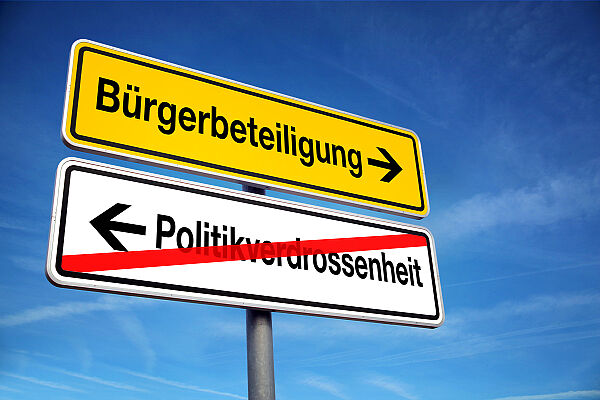 Bürgerbeteiligung Wegweiser vor blauem Himmel: Bürgerbeteiligung gelb mit Pfeil, Politikverdrossenheit links ist durchgestrichen (Bild: Coloures-Pic/Adobe Stock)