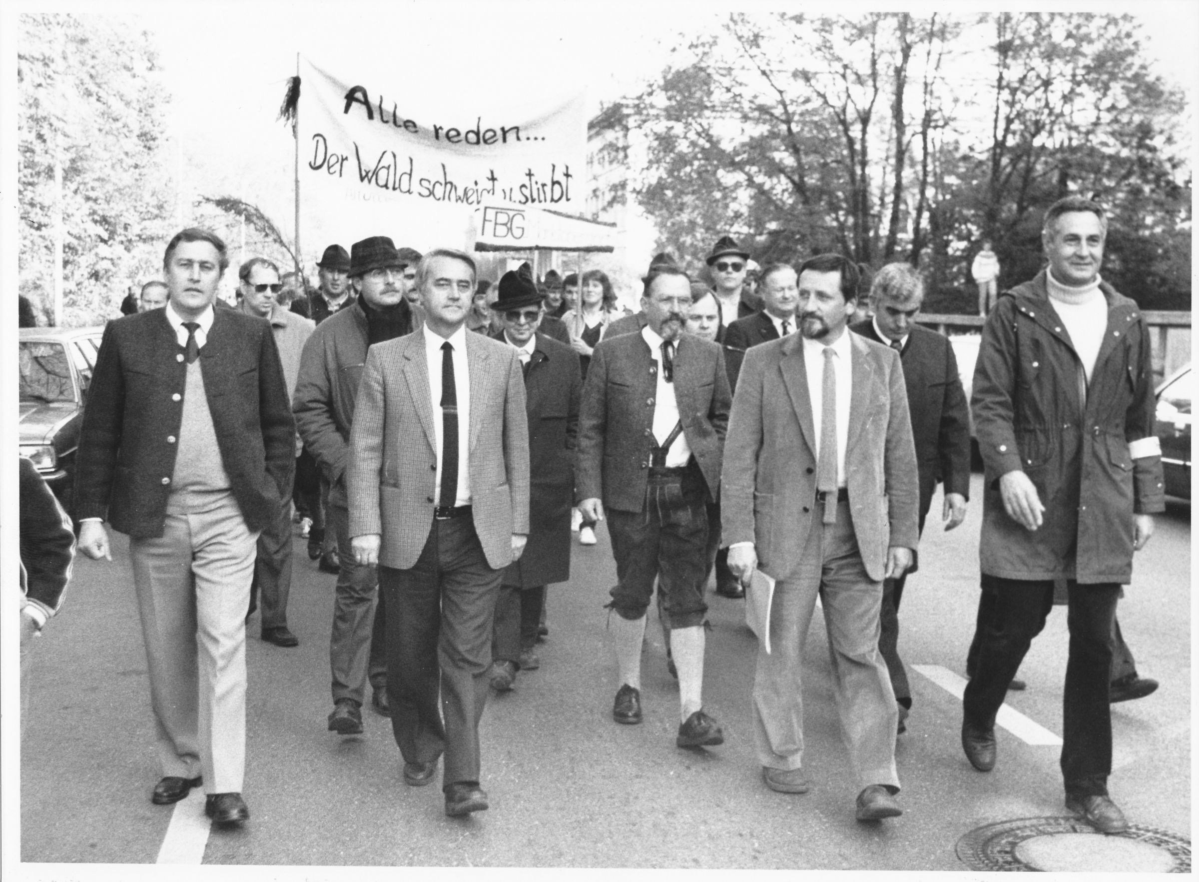 München 1984: Der damalige BN-Vorsitzende Hubert Weinzierl (2.v.re) und der BN-Geschäftsführer Helmut Steininger (1.v.re.) auf einer Demonstration gegen das Waldsterben. (Foto: BN-Archiv) Eine Gruppe von Menschen demonstriert mit einem handgeschriebenen Banner gegen das Waldsterben (Foto: BN-Archiv)