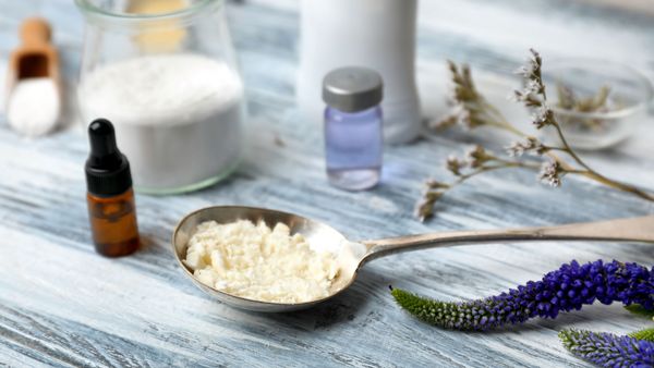 Deo selber machen: Auf einem Holztisch stehen Zutaten für ein Do It Yourself Sprüh-Deodorant. Es sind Natronpulver und ein ätherisches Öl.