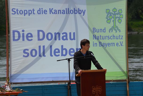 Ein Mann steht an einem Rednerpult vor einem Banner mit der Aufschrift "Die Donau soll leben". Der BN kämpft seit Jahrzehnten für eine frei fließende Donau. (Foto: Holger Lieber)