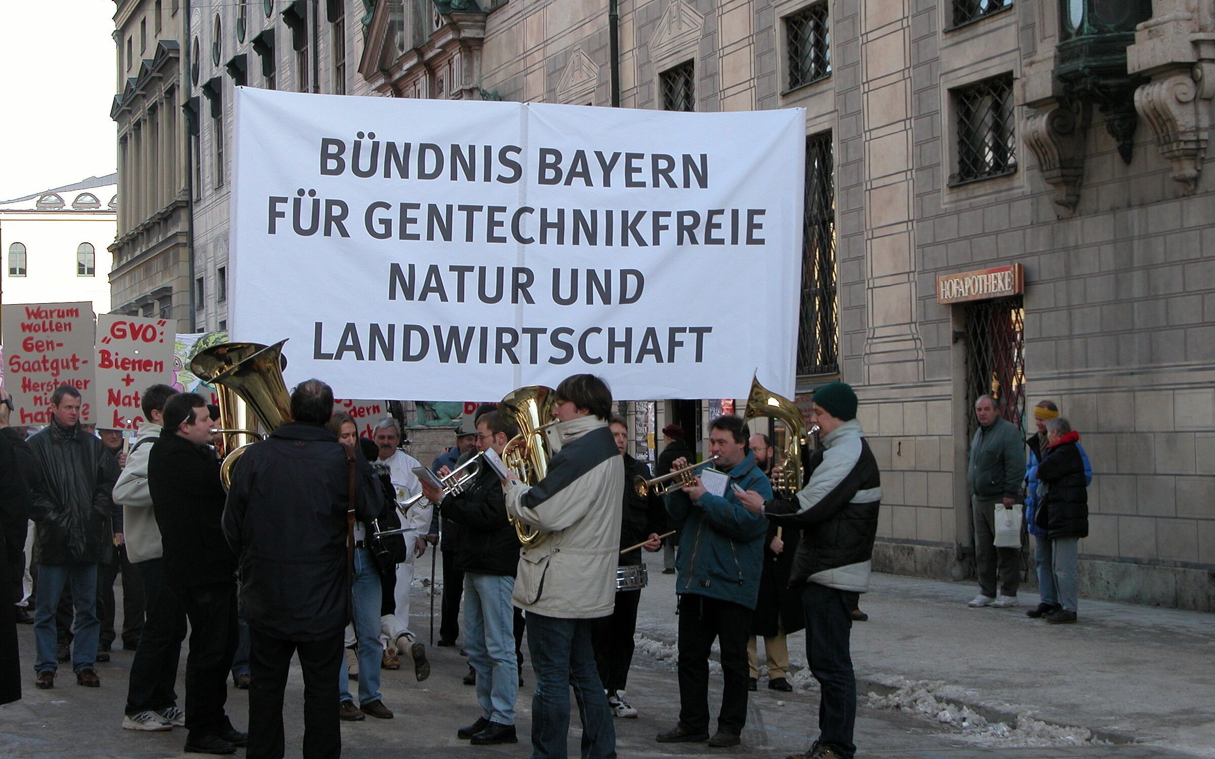 Foto: BN Mitglieder des Bündnis Bayern für gentechnikfreie Natur und Landwirtschaft demonstrieren mit einem großen weißen Banner und einer Blaskapelle in München