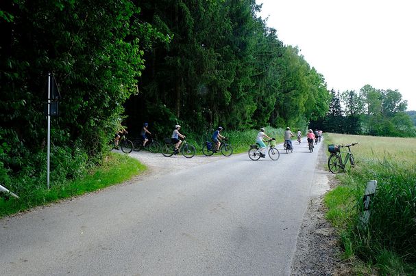 Die teilnehmenden Radler biegen flott aus einem Waldweg auf die Straße