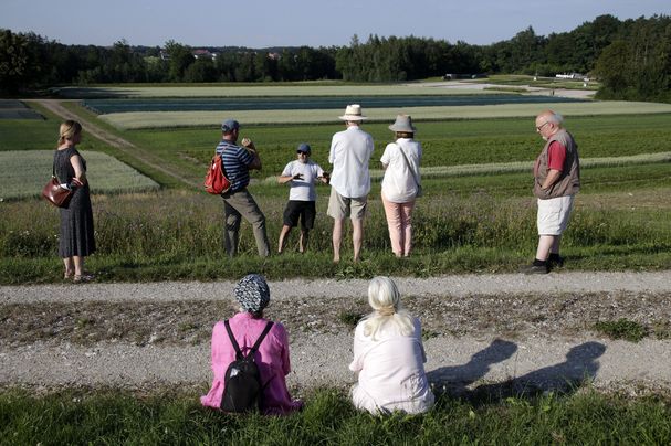 Personen sehen sich den Pflanzgarten an und lauschen einem Vortragenden