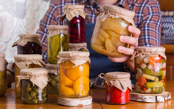 Lebensmittel konservieren: Vergleich der Konservierungsmethoden. (Foto: aamulya/stock.adobe.com) Lebensmittel konservieren: Ein Mann hält ein Glas mit konserviertem Gemüse in der Hand, weitere Gläser stehen auf einem Tisch.