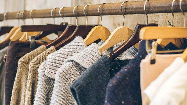 Kaufen Sie nur, was Sie wirklich brauchen und achten Sie dabei auf Langlebigkeit und zeitloses Design. (Foto: Roxana Jifcovici) Nachhaltige Kleidung: Eine Auswahl hochwertiger Pullover hängt an Bügeln an einer Stange.