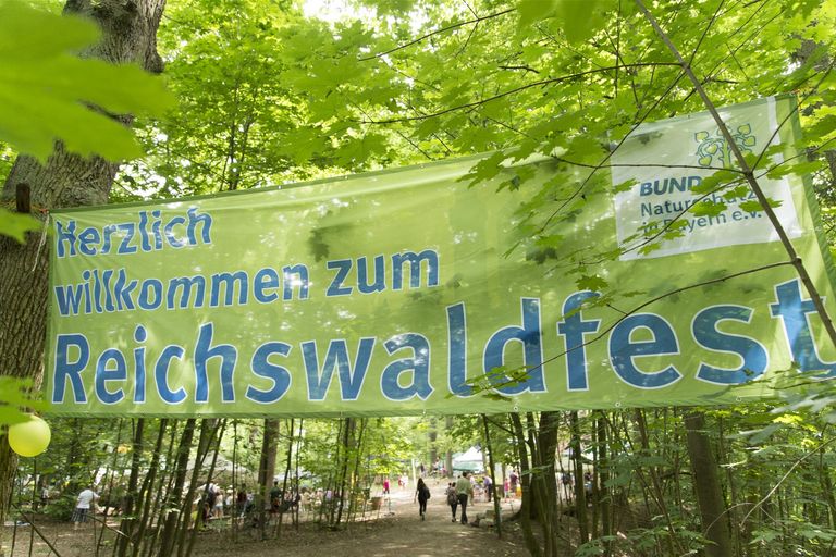 Ein Banner hängt im Wald mit der Aufschrift Herzlich Willkommen zum Reichswaldfest (Foto: Toni Mader)