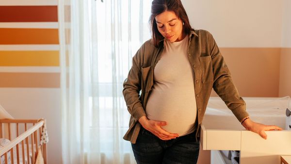 Schwangerschaft ohne Schadstoffe: Eine schwangere Frau steht im künftigen Kinderzimmer. Sie lächelt und hält sich mit einer Hand denBauch.