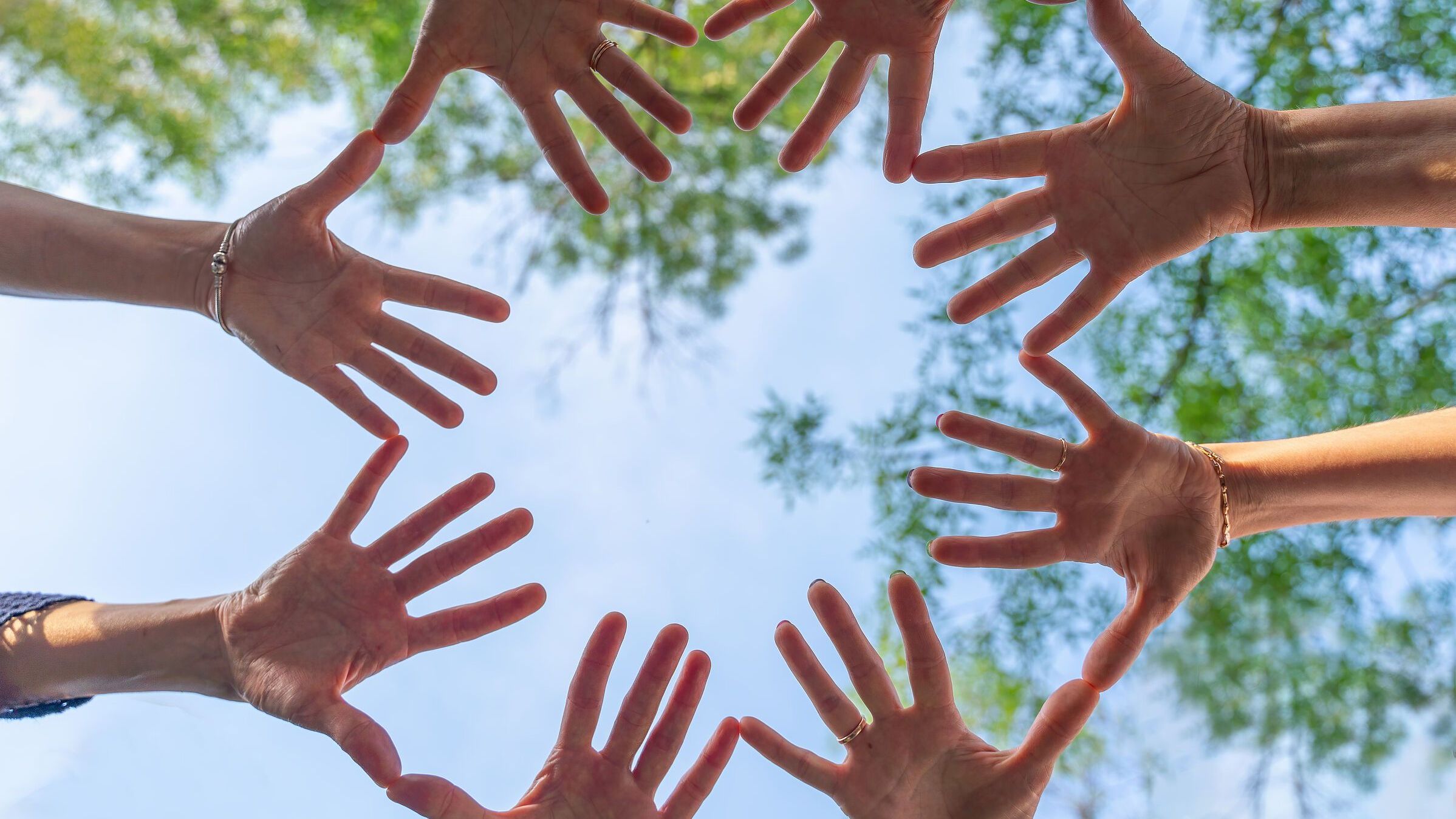 Hände werden im Kreis vor den blauen Himmel gehalten. (Bild: Svetograph)