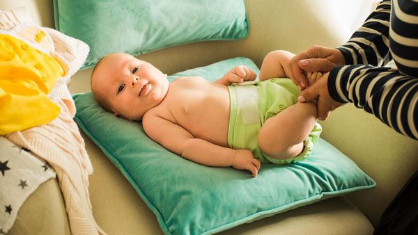 Stoffwindeln sind besonders umweltfreundlich, wenn man sie energieeffizient wäscht, auf den Trockner verzichtet und auf schadstofffreie Materialien achtet. (Foto: oksix/stock.adobe.com) Stoffwindeln richtig nutzen: Eine Mutter wechselt die grüne Stoffwindel ihres Babys.