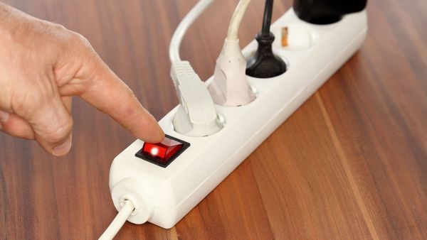 Stand-By-Schaltungen verbrauchen enorm viel Strom. Deshalb Geräte oder Steckerleisten immer ganz ausschalten. (Foto: rupbilder/stock.adobe.com) Stand-By vermeiden: Mann schaltet Steckerleiste aus.