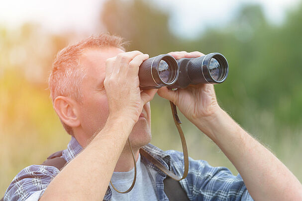 Mann mit Fernglas bei der Beobachtung der Natur (Foto: Monika Wisniewska /stock.adobe.com)
