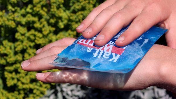 Jemand kühlt einen Wespenstich an seiner Hand mit einem Icepack
