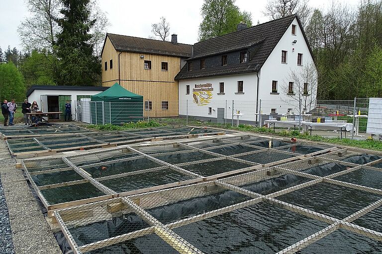 (Foto: Manfred Köhler) Ein saniertes altes Gebäude mit einem neuen Holzanbau und vielen Wasserbecken im Vordergrund