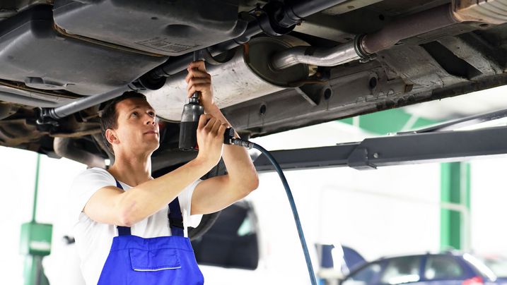 Ein Automechaniker arbeitet am Katalysator eines Fahrzeugs (Foto: indeustrieblick/fotolia.com).
