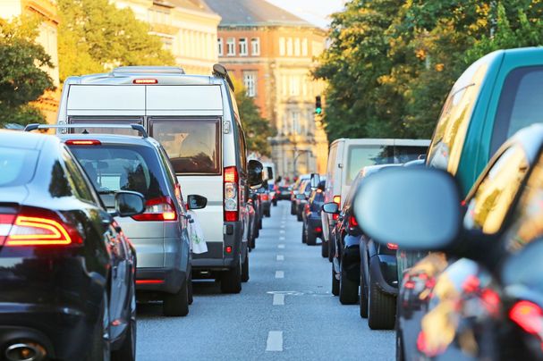 Autos stauen sich zweispurig in langen Schlangen vor einer Ampel: Der wachsende Autoverkehr fordert immer mehr Platz und führt zu wachsenden Luft-, Lärm- und Umweltproblemen. (Bild: Adobestock/Kara)